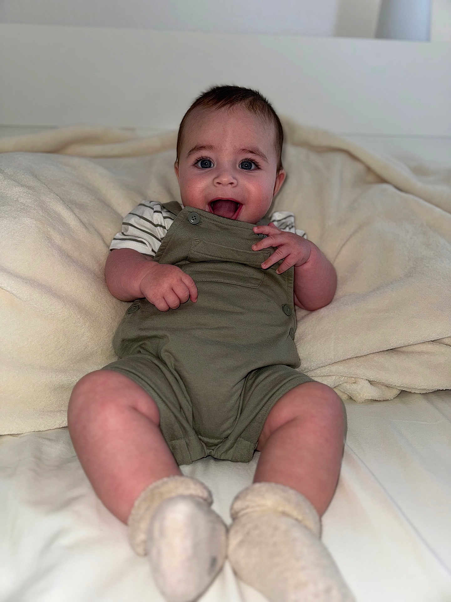 Gaspard a rejoint le concours — aidez-le/la à gagner de superbes lots ! baby, infant, smiling, overalls, socks, blue_eyes, happy, cute, sitting, blanket, indoor, portrait, child, soft_texture, clothing, person, face, skin, young, cozy