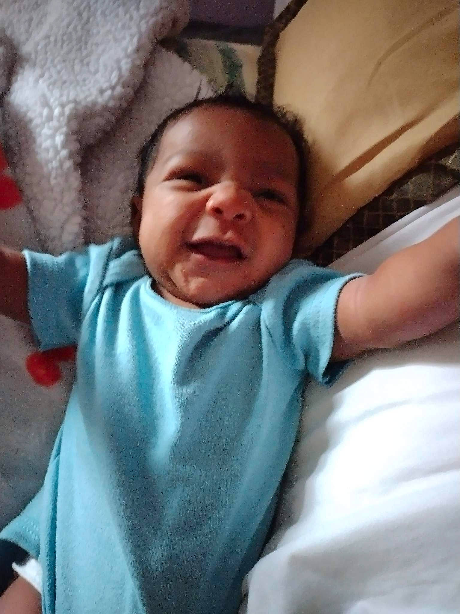 Ronald is registered to the contest to win money with this photo: baby, cheek, chin, comfort, cool, eye, eyebrow, finger, gesture, happy, head, linens, lip, mouth, nose, person, skin, sleeve, smile, textile