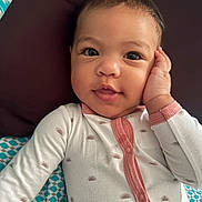 Maylee joined the competition — help win amazing prizes! baby, infant, face, smile, hand, onesie, clothing, pillow, blanket, pattern, cute, child, portrait, skin, eyes, sleepwear, resting, indoors, young, person
