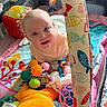 baby, child, playpen, toy, colorful, smiling, blanket, plush, face, infant, cute, happy, indoors, fabric, pattern, seating, soft, playtime, person, comfort