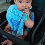 baby, child, stroller, spoon, bib, blue, chewing, face, hand, foot, infant, seat, clothing, indoor, person, closeup, curious, sitting, toy, expression