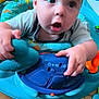 baby, child, infant, toy, activity_center, blue, play, curious, indoor, floor, colorful, plastic, hand, face, expression, closeup, seat, crawling, person, young