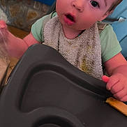 Melyo participe au concours pour gagner de l'argent avec cette photo : toddler, child, high_chair, bib, messy, curious, indoor, face, expression, clothing, hand, tray, kitchen, floor, laundry_basket, pile_of_clothes, person, young_child, real_photo, casual