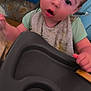 toddler, child, high_chair, bib, messy, curious, indoor, face, expression, clothing, hand, tray, kitchen, floor, laundry_basket, pile_of_clothes, person, young_child, real_photo, casual