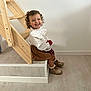 child, toddler, smile, curly_hair, bow, white_blouse, brown_skirt, shoes, stairs, wood, floor, indoor, happy, sitting, person, cute, young_child, portrait, home, casual