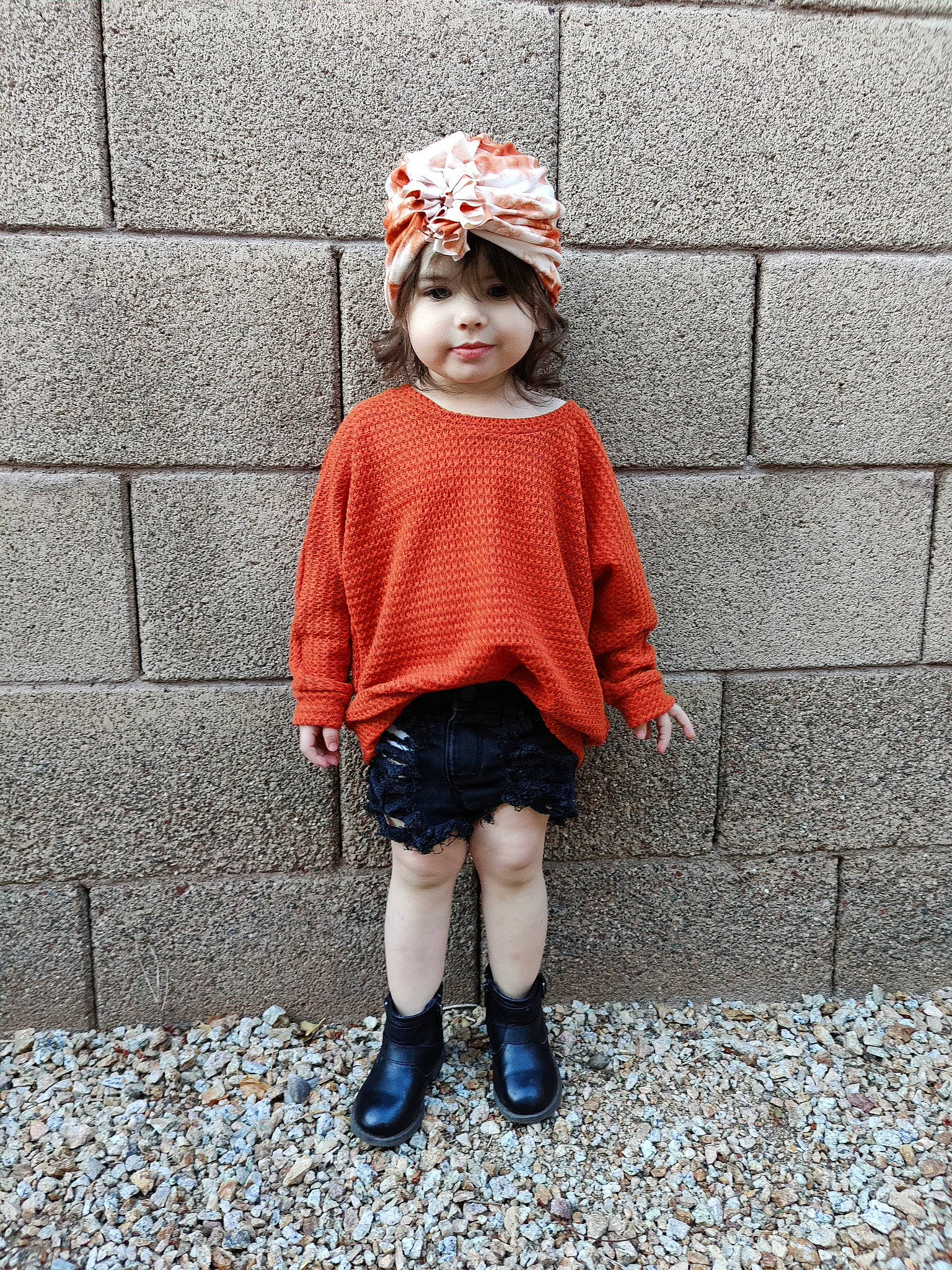 Quinn is registered to the contest to win money with this photo: arm, baby_toddler_clothing, brick, brickwork, child, denim, headgear, headwear, helmet, human_leg, knee, pattern, people, person, personal_protective_equipment, plant, pumpkin, sleeve, street_fashion, t_shirt