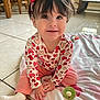 baby, toddler, child, smiling, sitting, headband, heart_pattern, pink_pants, onesie, blanket, toy, tile_floor, earrings, dark_hair, big_eyes, indoors, natural_light, portrait, cute, playtime