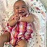 baby, smiling, romper, colorful_clothing, floral_blanket, infant, happy, cute, hands, lying_down, cheeks, skin, head, legs, toes, expression, indoors, soft_texture, pattern, child