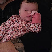 Lilith is registered to the contest to win money with this photo: baby, sleeping, floral_onesie, infant, tattoo, arm, adult, close_up, indoor, portrait, peaceful, resting, child, person, skin, hand, clothing, holding, cute, newborn