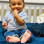 Aev Netik is registered to the contest to win money with this photo: baby, barefoot, blanket, child, cozy, crib, cute, hand_in_mouth, happy, home, indoor, infant, jeans, pillow, playful, portrait, sitting, smiling, striped_shirt, young_child