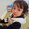 Franco is registered to the contest to win money with this photo: child, toddler, baby, portrait, face, eyes, hair, looking_at_camera, indoor, playroom, baby_carrier, clothing, black_and_white, toy, storage_bins, carpet, home, sitting, curious, photography