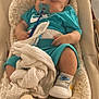 apparel, baby, baby_boy, baby_rocker, blanket, child, clothing, comfort, cushion, cute, footwear, indoor, infant, pacifier, relaxation, resting, sleeping, sneakers, toddler, young_child