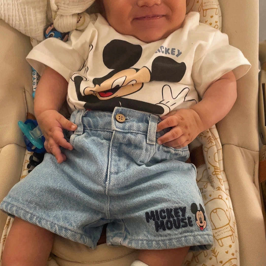 Mariano a rejoint le concours — aidez-le/la à gagner de superbes lots ! animal_print, baby, baby_seat, baby_toys, child, clothing, comfort, cushion, cute, denim_shorts, happy, indoors, infant, mickey_mouse, pattern, person, portrait, smiling, socks, tshirt