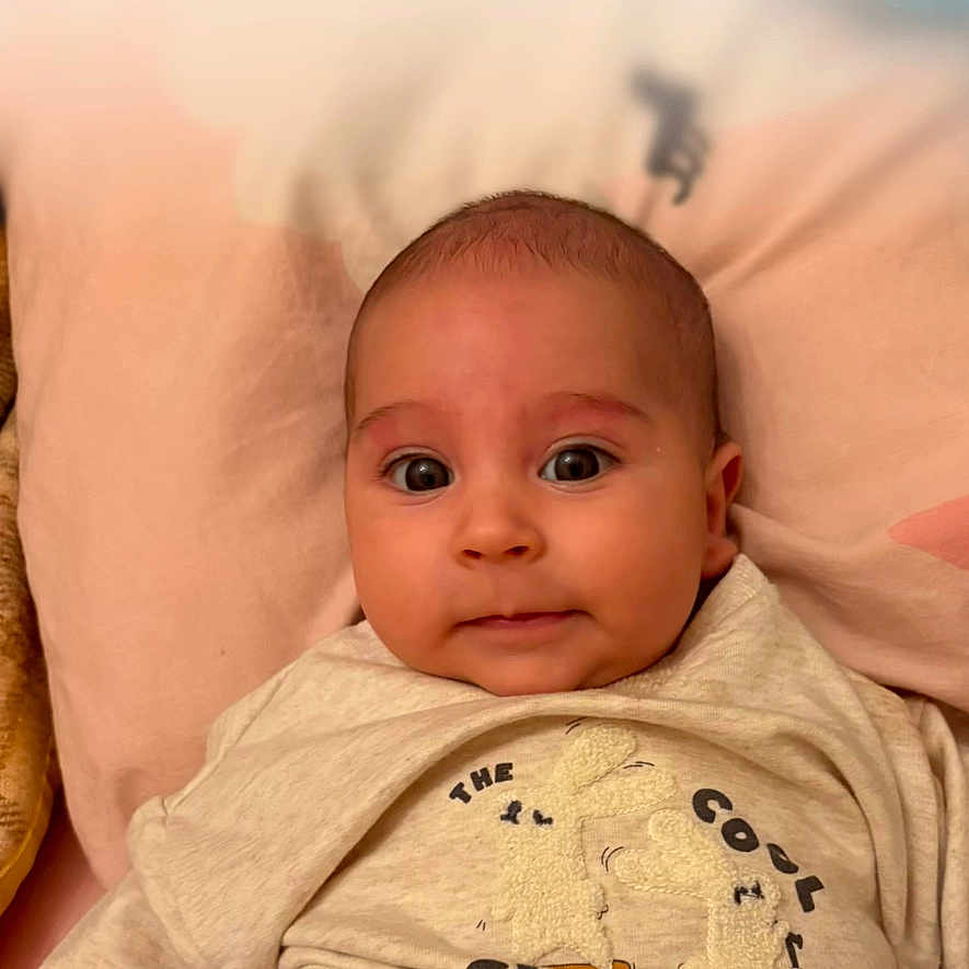 Mattia a rejoint le concours — aidez-le/la à gagner de superbes lots ! baby, infant, face, clothing, laying_down, beige, soft_surface, cute, wide_eyes, sleeper, sweater, phone_lock_screen, time_display, date_display, icons, text_overlay, cozy, indoors, portrait, child