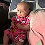 baby, child, pink_clothing, hello_kitty, onesie, pillow, cushion, indoor, portrait, smiling, face, head, hands, legs, seated, cozy, soft_fabric, cute, toddler, infant