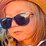 child, hat, straw_hat, sunglasses, blond_hair, long_hair, outdoor, sunlight, golden_hour, portrait, face, fashion, casual_clothing, person, young, cool, accessory, reflection, closeup, warm_light