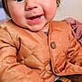 baby, child, smiling, jacket, orange_jacket, portrait, cute, happy, face, person, indoor, clothing, young_child, warm_clothes, buttoned_jacket, sitting, closeup, skin, hair, eyes