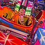 amusement_park, amusement_ride, backpack, blonde_hair, bright_colors, carnival, child, colorful_lights, entertainment, family_fun, fun, indoor, person, playful, ride, seat, smiling, toddler, toy_car, young_child