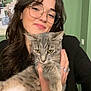 woman, cat, glasses, smile, indoor, pet, holding, gray_cat, long_hair, jewelry, bracelet, ring, green_wall, portrait, casual, happy, feline, household, cute, cozy