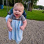 baby, infant, child, swing, playground, smiling, happy, park, grass, trees, gravel, blue_blanket, onesie, hands, face, seat, chain, summer, outdoor, joy