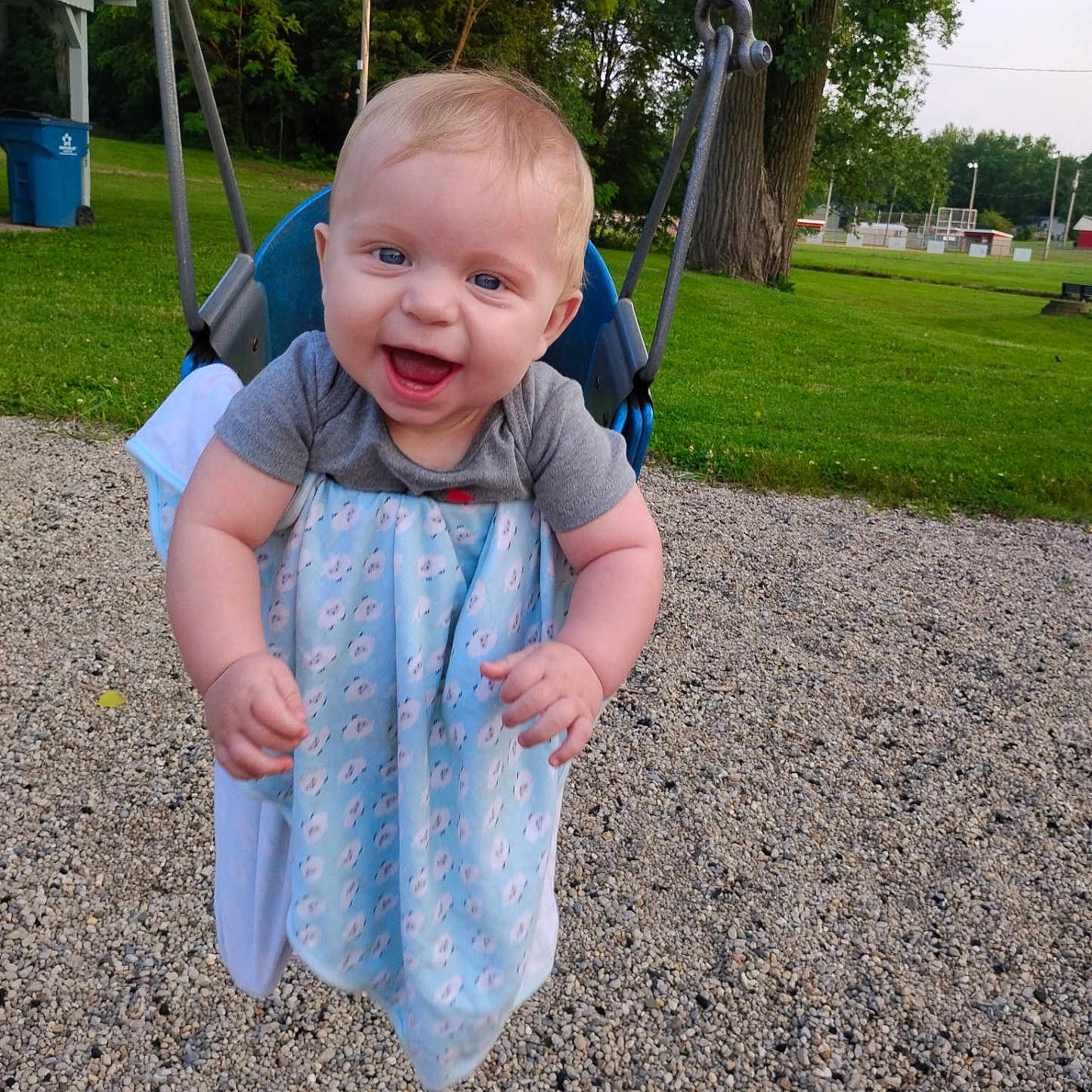 Axel Del joined the competition — help win amazing prizes! baby, blue_blanket, chain, child, face, grass, gravel, hands, happy, infant, joy, onesie, outdoor, park, playground, seat, smiling, summer, swing, trees