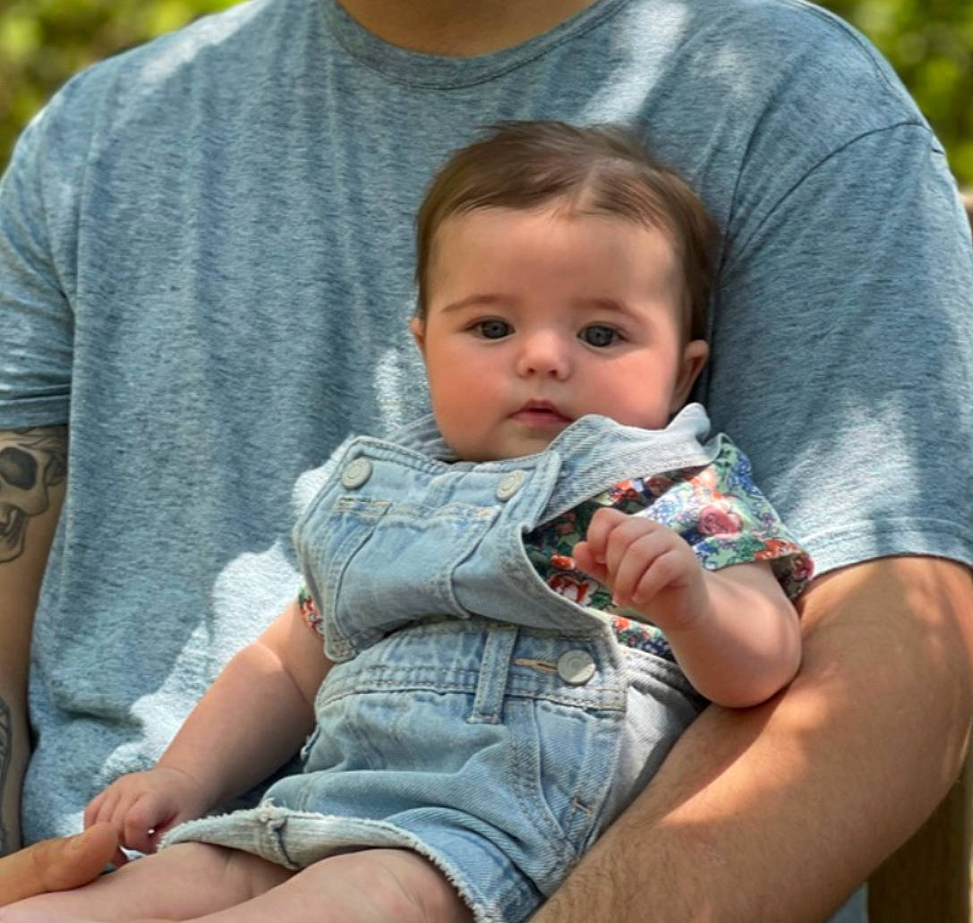 Lorelei is registered to the contest to win money with this photo: baby, baby_toddler_clothing, child, comfort, cool, eye, facial_expression, grass, hairstyle, happy, human, lap, leg, leisure, mammal, person, skin, summer, t_shirt, toddler