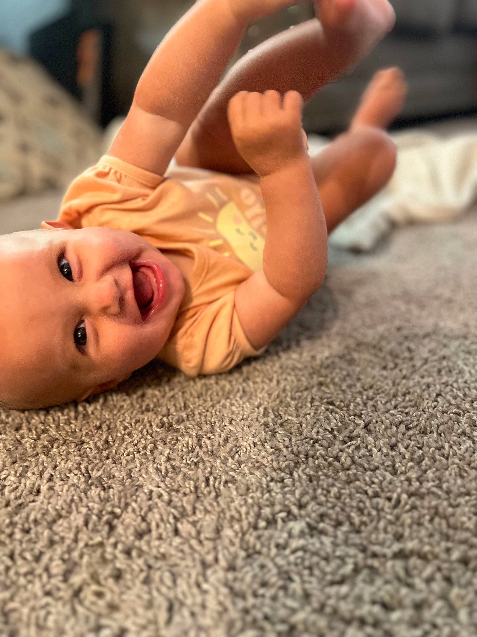Eleanor is registered to the contest to win money with this photo: arm, comfort, finger, flooring, fun, gesture, grass, hand, happy, head, human_body, joint, mouth, muscle, nose, person, skin, smile, thumb, toddler