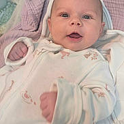 Skyler is registered to the contest to win money with this photo: baby, blanket, child, cozy, cute, expression, face, happy, head, indoors, infant, lying_down, newborn, onesie, person, portrait, skin, sleepwear, smiling, soft