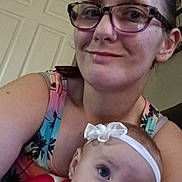 Lilly Mei is registered to the contest to win money with this photo: woman, baby, glasses, headband, smile, indoor, door, tank_top, earrings, person, child, portrait, face, skin, hair, home, curious, holding, casual, closeup