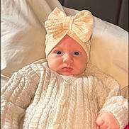 Camélia participe au concours pour gagner de l'argent avec cette photo : baby, blanket, blue_eyes, bow, child, clothing, cozy, cute, expression, face, hand, headband, indoors, infant, knit_sweater, person, pillow, portrait, soft_light, warm_colors