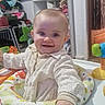 baby, child, smiling, indoor, toys, baby_activity_center, colorful, face, person, clothing, hand, play, furniture, sitting, happy, infant, cute, room, home, early_childhood
