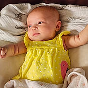 Delilah is registered to the contest to win money with this photo: baby, infant, newborn, child, face, eyes, arm, hand, yellow_dress, polka_dot, blanket, swaddle, cloth, leather_sofa, zebra_print, portrait, indoor, soft_lighting, cute, smile