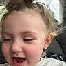 child, toddler, face, smiling, happy, earrings, hair, messy_bun, inside_car, seat, window, natural_light, closeup, person, cute, joyful, skin, eyelashes, mouth_open, casual_clothing