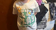 Amelia is registered to the contest to win money with this photo: child, girl, standing, tshirt, sneakers, clothing, indoor, floor, door, pile_of_clothes, casual, young, smiling, person, portrait, cute, standing_pose, fashion, floor_tiles, home