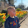 Isaac participe au concours pour gagner de l'argent avec cette photo : toddler, child, outdoor, spring, flowers, tulips, sunny, nature, pathway, sweatshirt, colorful_text, curly_hair, portrait, side_profile, daylight, garden, young_child, casual_clothing, greenery, peaceful