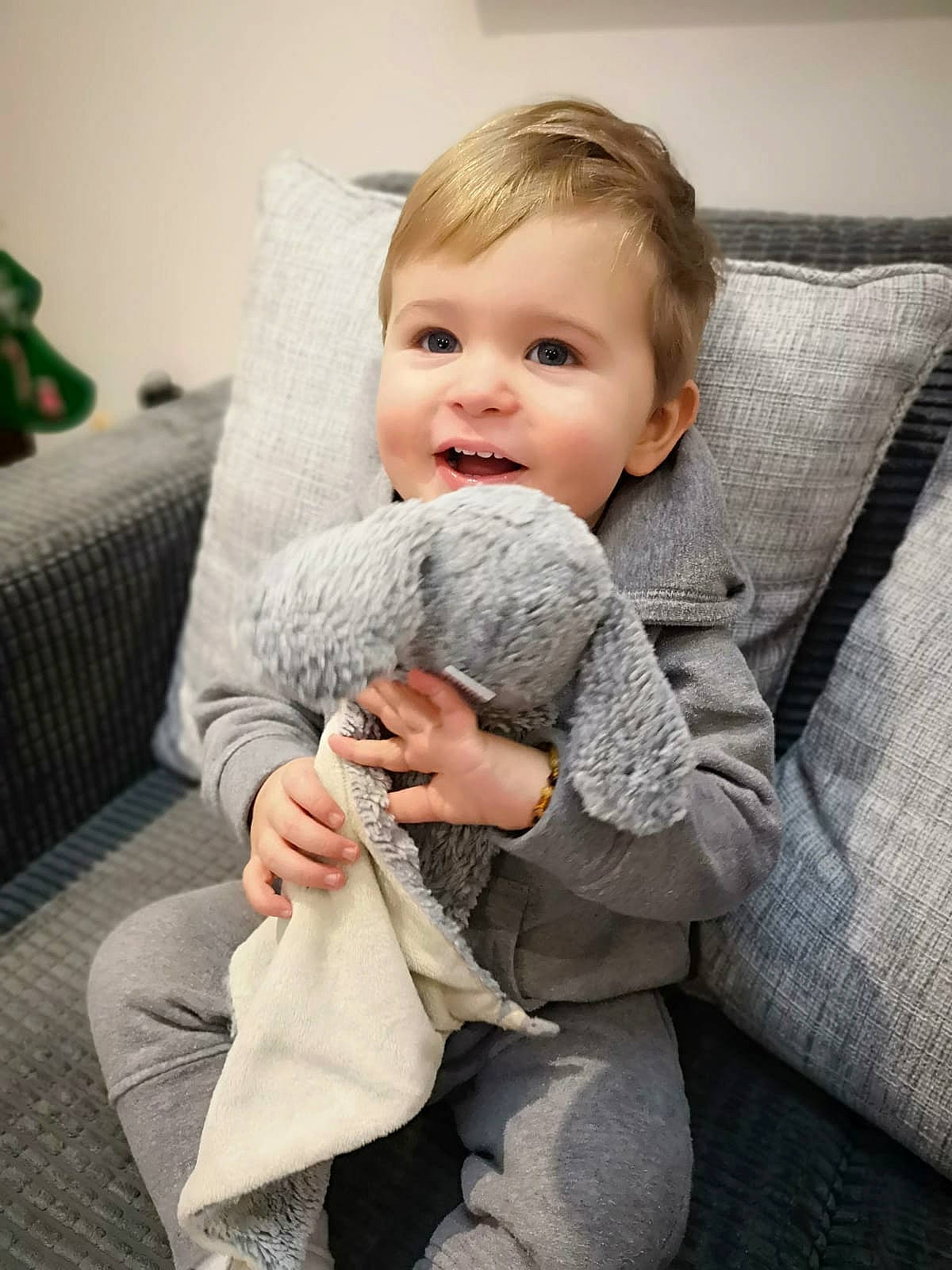 Fletcher is registered to the contest to win money with this photo: arm, baby, blanket, cheek, child, comfort, fur, hand, leg, linens, nose, person, room, sitting, skin, toddler