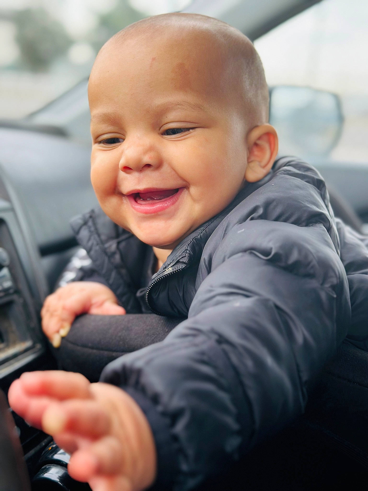 Lionel is registered to the contest to win money with this photo: auto_part, automotive_design, automotive_exterior, baby, baby_toddler_clothing, child, family_car, fun, gesture, happy, joy, luxury_vehicle, motor_vehicle, person, product, skin, sleeve, smile, steering_wheel, thumb