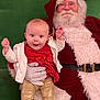 baby, beard, celebration, chair, child, christmas, festive, glasses, gloves, gold_leggings, green_background, happy, holiday, indoor, people, portrait, red_dress, santa_claus, smiling, white_jacket