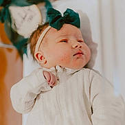 Blakely joined the competition — help win amazing prizes! baby, infant, headband, bow, white_onesie, sleepwear, face, skin, cheeks, hand, newborn, lying_down, indoors, soft_lighting, blurred_background, peaceful, cute, child, portrait, toddler