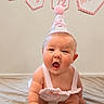 baby, infant, party_hat, birthday, half_birthday, celebration, pink, banner, cute, child, sitting, blanket, expression, indoors, smile, young_child, headwear, adorable, person, event