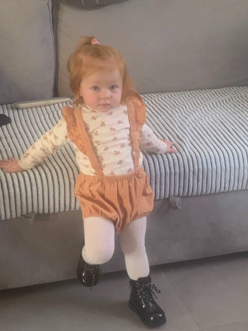 Giulia participe au concours pour gagner de l'argent avec cette photo : arm, baby_toddler_clothing, comfort, couch, dress, finger, floor, flooring, footwear, human_leg, knee, leg, person, shoulder, skin, sleeve, sock, standing, thigh, toddler