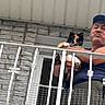 Minerva joined the competition — help win amazing prizes! animal, balcony, building, calico_cat, cap, casual_clothing, cat, daylight, fence, funny_face, holding, man, outdoor, person, pet, portrait, railing, resting, stone_wall, window