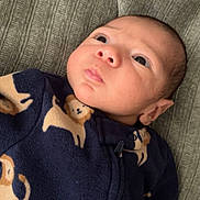 Hermes is registered to the contest to win money with this photo: baby, infant, face, clothing, onesie, lion_print, blue, blanket, texture, portrait, child, cute, resting, looking_up, indoors, soft_fabric, newborn, sleepwear, person, young