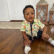 Leny is registered to the contest to win money with this photo: toddler, child, indoor, wooden_floor, shirt, dinosaur_pattern, socks, furniture, lantern, decor, curly_hair, expression, sitting, floor, home, person, casual_clothing, bracelet, door, bright