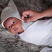 Viraj Bansal is registered to the contest to win money with this photo: baby, infant, blanket, hat, hand, fur_rug, texture, white, soft, cozy, cute, newborn, portrait, lying_down, skin, face, child, sleepwear, warm, comfort