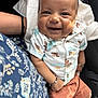 baby, smiling, child, shirt, shorts, bracelet, person, happy, sitting, lap, fabric, patterned_clothing, cute, indoor, portrait, skin, face, arm, casual, closeup