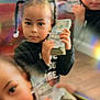 blur, braids, cash, casual_clothing, child, closeup, currency, expression, face, hands, holding, indoor, indoor_lighting, money, person, portrait, reflection, stack, wooden_floor, young