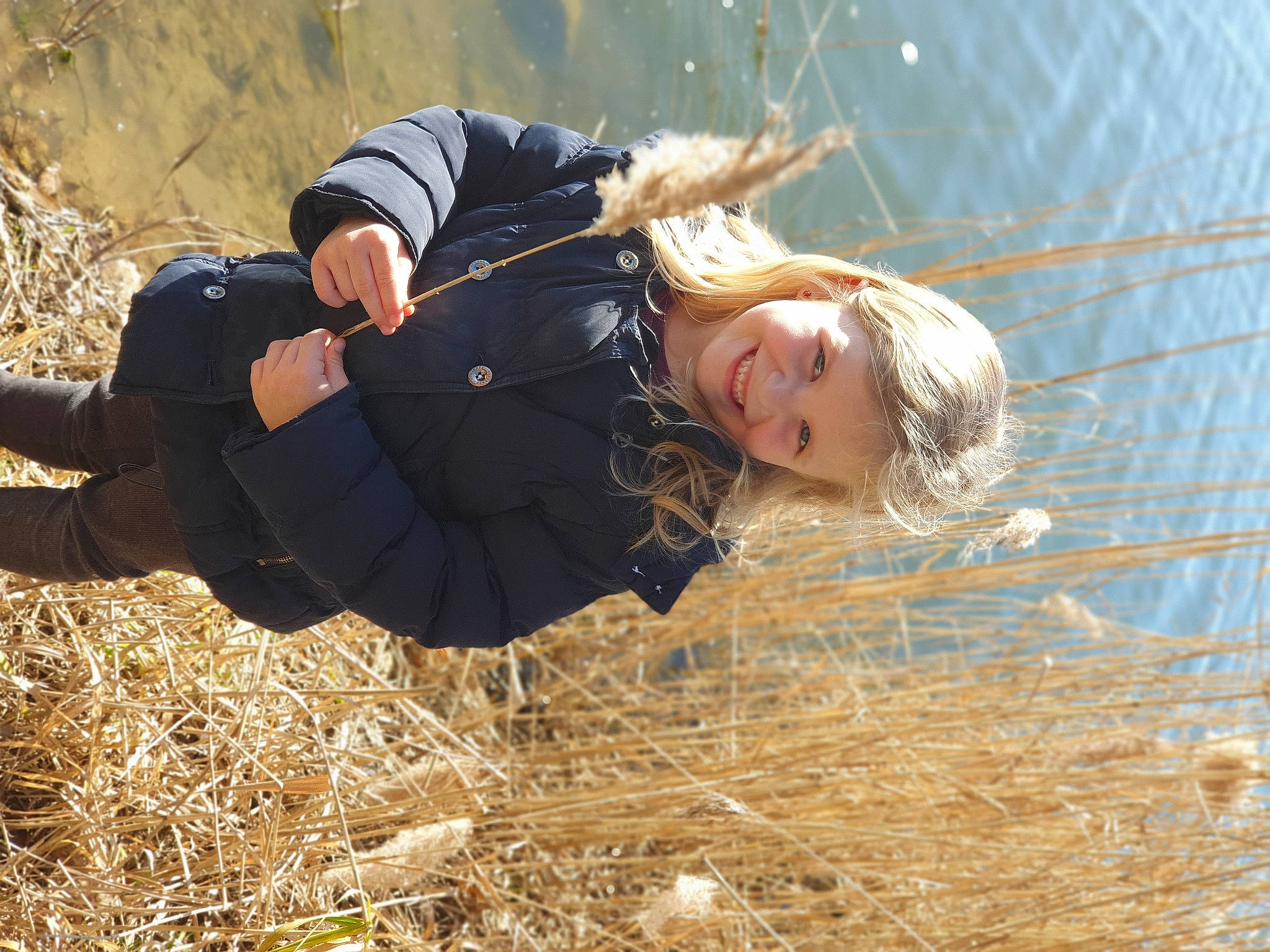 Angelina a rejoint le concours — aidez-le/la à gagner de superbes lots ! blond, boot, child, fun, grass, grass_family, grassland, happy, human_body, jacket, joy, leisure, people_in_nature, person, plant, recreation, sitting, smile, tree, water