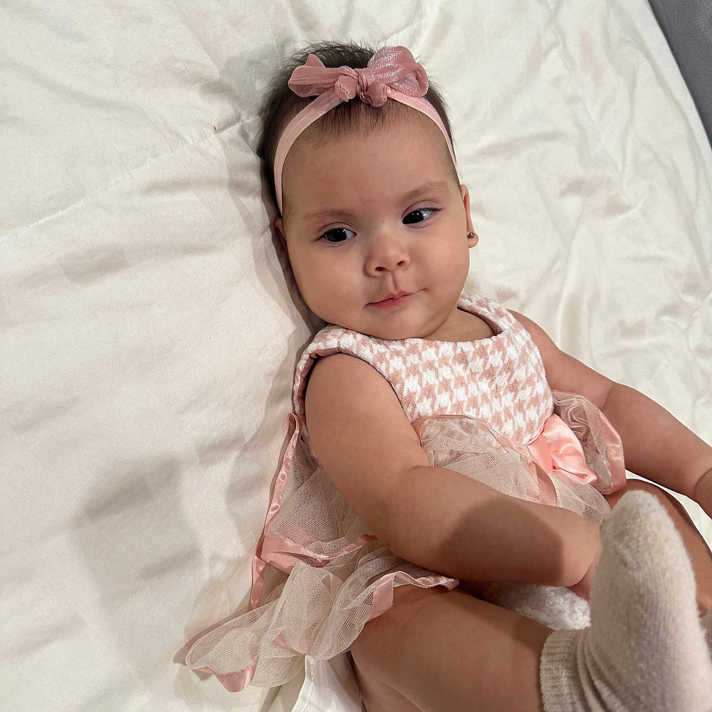 Jade joined the competition — help win amazing prizes! baby, child, infant, pink_headband, dress, sock, foot, bed, blanket, cute, playful, lying_down, indoors, person, young_child, portrait, soft_lighting, skin, headwear, apparel