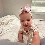 Jade joined the competition — help win amazing prizes! baby, child, infant, pink_bow, headband, bed, blanket, crawling, smiling, indoor, window_blinds, white_sheets, cute, happy, person, young_child, playful, soft_light, room, clothing